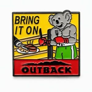 Outback‑themed pin showing a koala in a boxing ring holding a fork and knife, ready to dig into a hot, steaming steak.