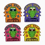 “Croc Star” lapel pins in four colors—orange, purple, pink, and yellow—each featuring a cartoon crocodile wearing sunglasses.”