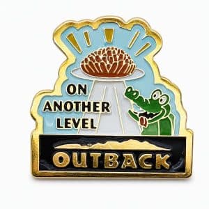 lapel pin showing a hungry croc looking up at a hot plate of Bloomin' Onion, with the phrase "On Another Level" and the Outback logo, crafted by The Pin Center