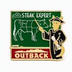 Kangaroo in graduation gear, pointing to a chalkboard with the phrase 'Steak Expert' and Outback logo, crafted by The Pin Center