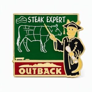 Kangaroo in graduation gear, pointing to a chalkboard with the phrase 'Steak Expert' and Outback logo, crafted by The Pin Center