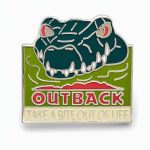 Glow-in-the-dark lapel pin featuring an angry looking croc saying "take a bite out of life" with the Outback logo, created by The Pin Center