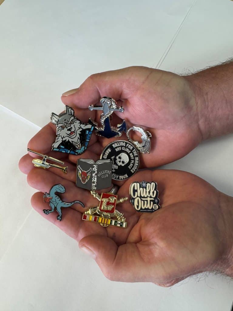 A close‑up view of assorted bro brooches arranged together, showcasing their bold metal finishes, sculpted details, and modern designs.